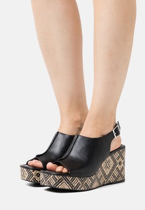 Černé kožené sandály na platformě s otevřenou špičkou a řemínkem kolem kotníku, s vzorovanou tkanou platformou s geometrickými detaily.