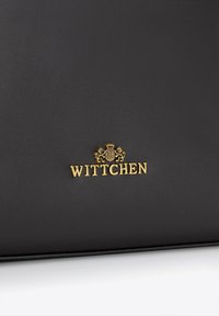 Czarna skórzana torba z teksturowaną powierzchnią i złotym logo "WITTCHEN" z motywami lwa powyżej. Prosty, nowoczesny design z czystymi liniami.