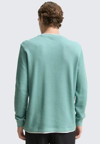Hellblaue Langarmshirt aus geripptem Stoff, mit Rundhalsausschnitt und schmalen Bündchen. Minimalistisches Design ohne sichtbare Muster.