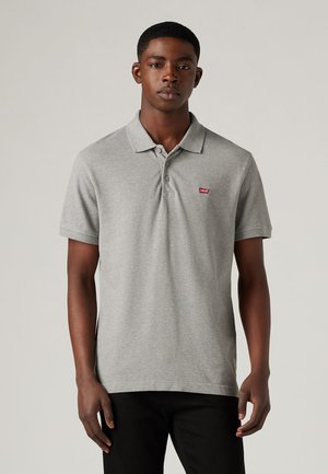 Grå polo skjorte med standard krage, korte ermer og en liten rød Levi's-logo på venstre bryst. Myk, strukturert stoff.