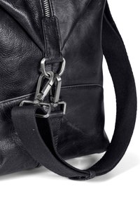Sac en cuir noir avec une surface texturée, quincaillerie en argent et une bandoulière en tissu contrastant. Détails de fermeture éclair et de serrure visibles.