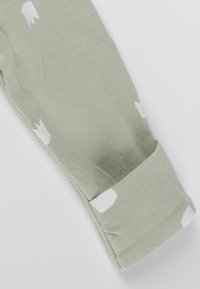 Leggings di cotone verde chiaro con motivi floreali bianchi. Presentano un risvolto piegato e una texture morbida, ideali per il comfort.