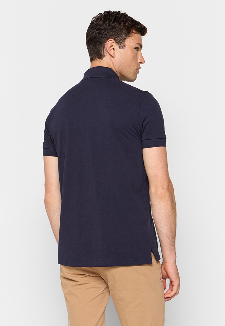Polo in blu navy con maniche corte, colletto a costine, aperture laterali e tessuto di cotone liscio. Progettato per un abbigliamento casual.