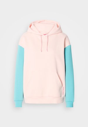 Sweat à capuche avec un corps rose et des manches turquoise. Comprend une poche avant et des cordons de serrage contrastants. Fabriqué en tissu doux.