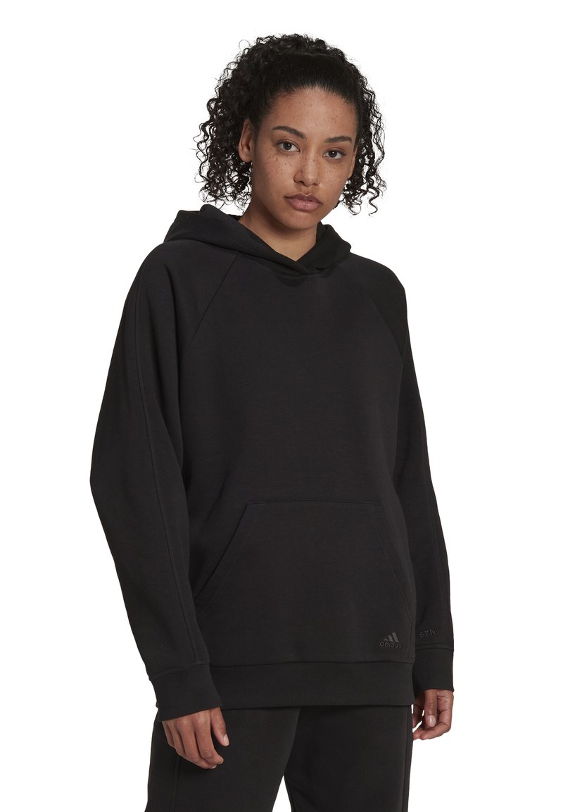 Schwarzer Hoodie aus weichem Stoff mit einer Kängurutasche, Raglanärmeln und gerippten Bündchen. Beinhaltet ein kleines Logo am unteren Ende.