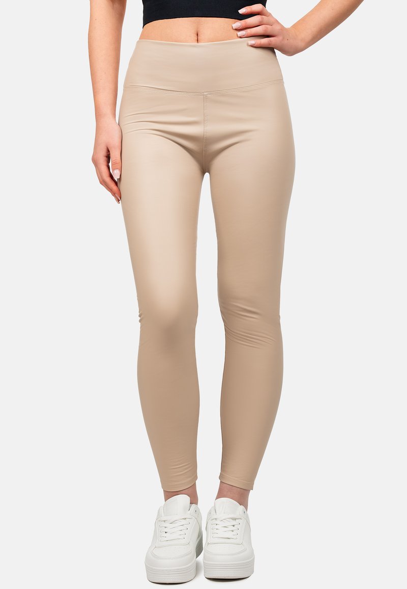 Leggings beige con vita alta, realizzati in un materiale morbido ed elastico. Abbinati a sneaker bianche, che evidenziano un design aderente.