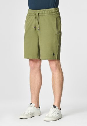 Pantaloni shorts khaki con vita elastica e cordino, dotati di tasche laterali e un piccolo logo nero sulla gamba sinistra.