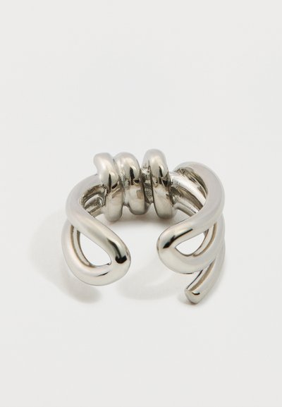 Inel argintiu metalic cu un design răsucit și deschis. Prezintă suprafețe netede și rotunjite și trei accente curbate în centru.