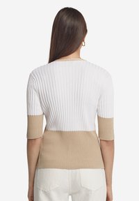 Ribbade tröja med en vit övre del och en beige nedre del. Korta ärmar, texturerat tyg och rundad halsringning.