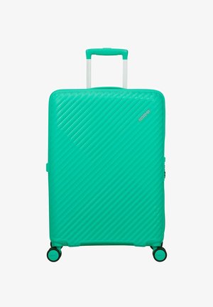 Teal hard-shell suitcase with diagonal ridges, four spinner wheels, telescopic handle, and small "American Tourister" logo on front.