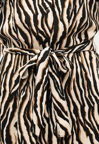 Μαύρο, καφέ και μπεζ φόρεμα με τύπωμα ζέβρας, με κουμπιά στο μπροστινό μέρος και ζώνη από ύφασμα δεμένη στη μέση.