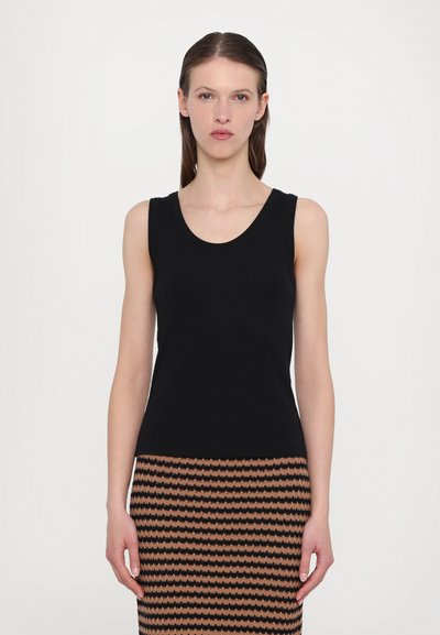 Débardeur noir à côtes avec un décolleté rond, associé à une jupe brune et noire à motifs avec des rayures ondulées.