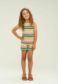 Top sin mangas a rayas en rosa pastel, amarillo y verde; pantalones cortos a juego con dobladillo con flecos. Sandalias marrones completan el conjunto.