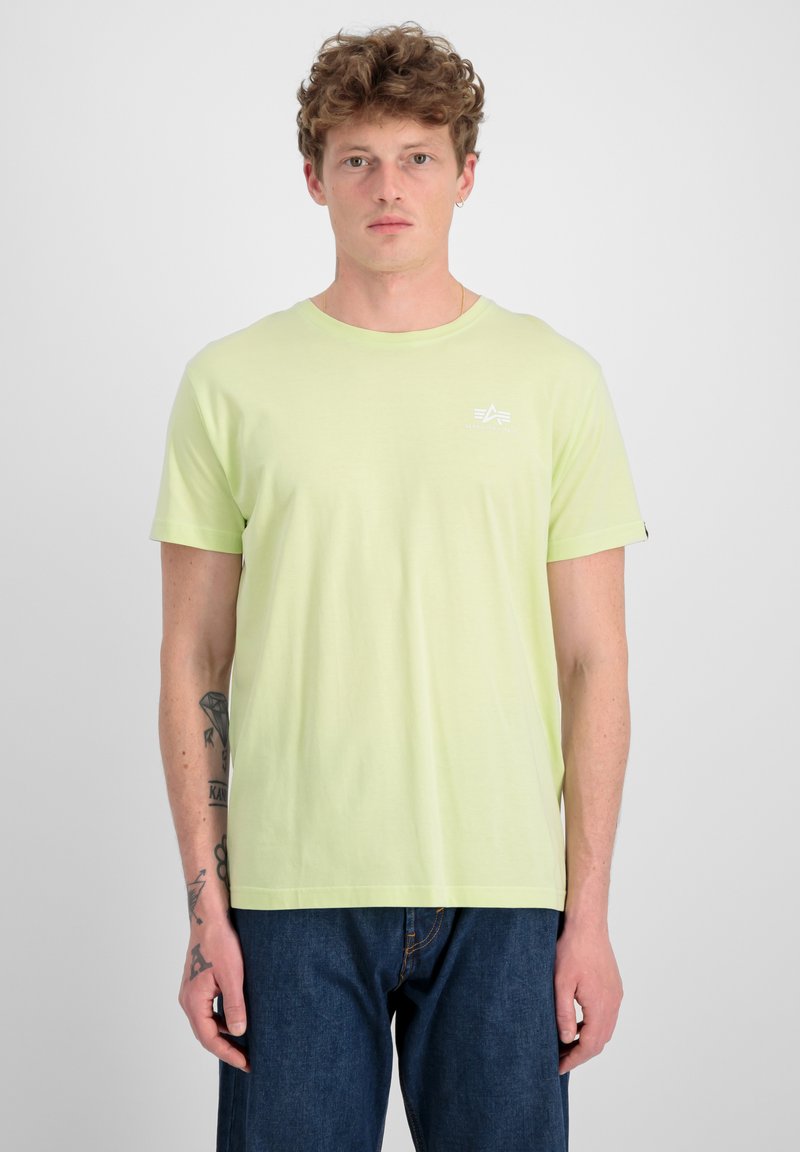 Kurze Ärmel, Rundhalsausschnitt T-Shirt aus leichtem limettengrünen Baumwollstoff, mit einem kleinen weißen Grafikdesign auf der Brust und umgeschlagenen Ärmeln.