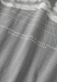 Tela gris con una superficie texturizada, con un patrón de cuadrícula y texto motivacional blanco en una fuente moderna.