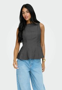 Grå peplum top med høj halsudskæring og lodrette sømme, parret med lyseblå afslappede jeans. Glat tekstur og struktureret design.