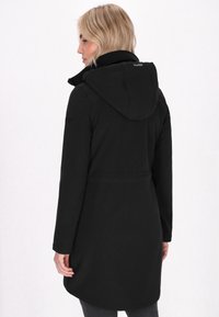 Schwarze wasserdichte Jacke mit Kapuze, die eine taillierte Taille, lange Ärmel und eine glatte Textur aufweist. Die Rückansicht zeigt einen abgerundeten Saum.