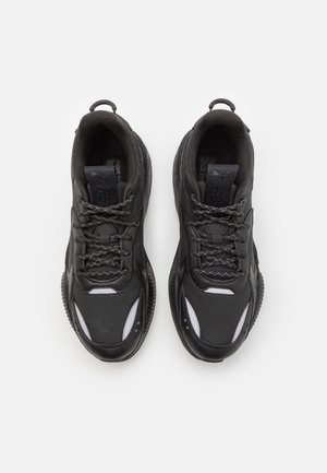 Par de zapatillas deportivas negras con detalles reflectantes, cierre de cordones y cuello acolchado, vistas desde arriba sobre un fondo blanco.