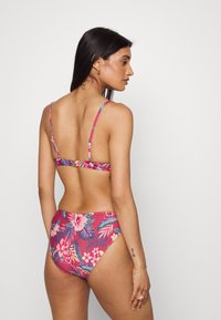 Blumiges Zweiteiler-Badeanzug in Pink mit tropischen Mustern. Verfügt über dünne Träger, einen V-förmigen Rücken und eine hochgeschnittene Unterteile mit vollständiger Abdeckung.
