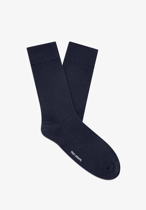 Para ciemnoniebieskich, prążkowanych skarpet za kostkę z białym logo nadrukowanym przy palcach na białym tle.