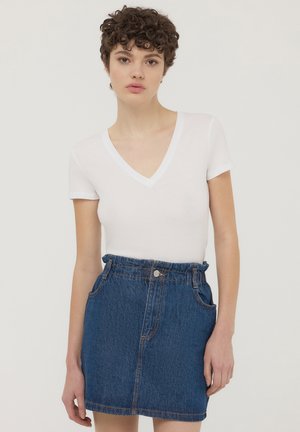 Biała koszulka z krótkim rękawem i dekoltem w serek, zestawiona z ciemnoniebieską mini spódniczką z denimu, wyposażoną w przednie kieszenie i lekko elastyczny pas.