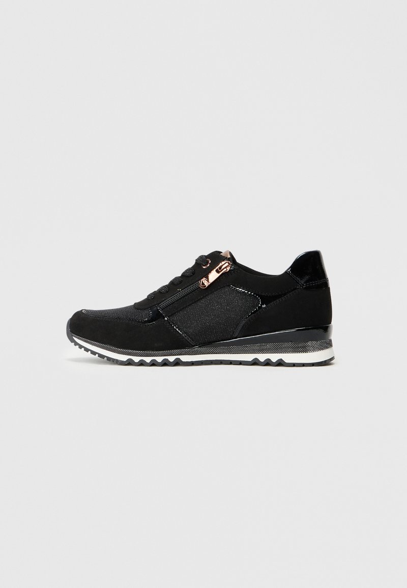 Sneaker nera realizzata con una combinazione di materiali opachi e lucidi. Presenta pannelli testurizzati, una zip decorativa e una suola a zigzag.