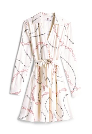 Kreminės medžiagos apvalkalo suknelė, puošta raudonais ir juodais grandinės raštais. Suknelė turi apykaklę, ilgus rank sleeves ir juosmens raištį.