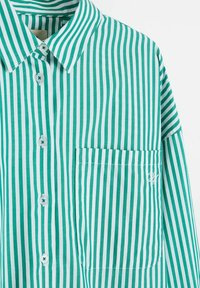Zielono-biała koszula w pionowe paski, zapinana na guziki, z kołnierzykiem i kieszenią na piersi, ozdobiona subtelnym białym haftem.