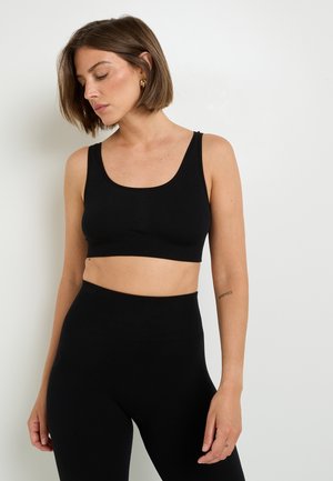 Cropped top nero a coste con scollatura a barca, abbinato a leggings neri a vita alta. Il tessuto è morbido ed elasticizzato, offrendo una silhouette aderente.