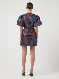 Abito a maniche a sbuffo in tessuto stampato con tonalità metallizzate di viola, arancione e nero, caratterizzato da una vita aderente e una lunghezza mini.