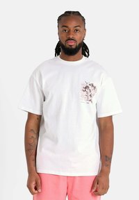 Wit katoenen T-shirt met een grafische opdruk op de linkerborst, met kleurrijke tekst en een bloemmotief. Korte mouwen; losse pasvorm.