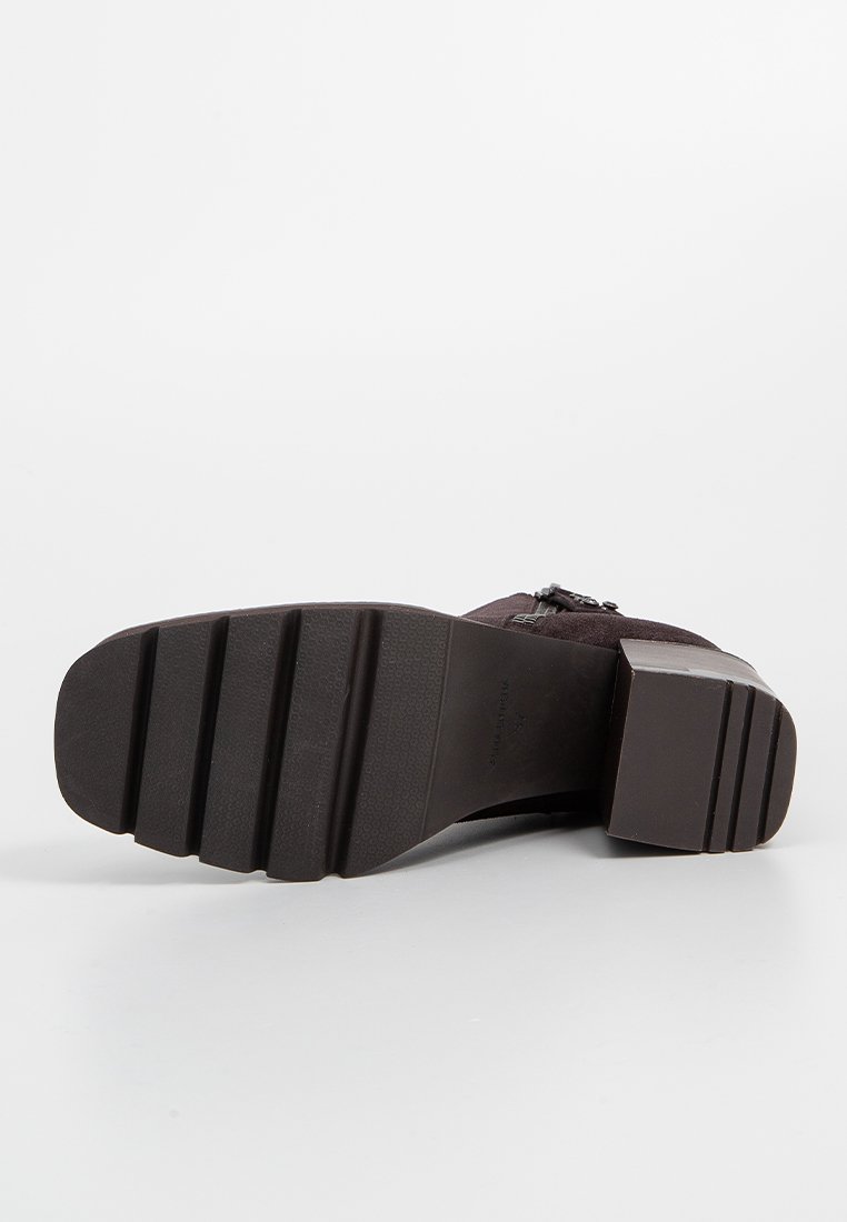 Bota marrón con una superficie texturizada, un tacón cuadrado y una suela de goma estriada. Presenta una cremallera lateral y un diseño elegante sin adornos.