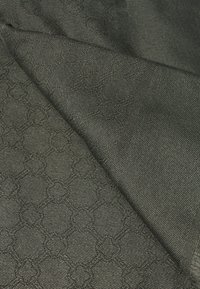 Tessuto intessuto nero con un motivo testurizzato di esagoni intrecciati. Il materiale presenta un leggero lucido con una finitura liscia.