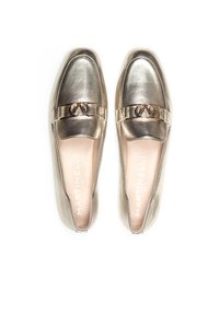 Mocasines metálicos dorados con un acabado de cuero suave, que presentan una correa decorativa y un acento de logo en la parte superior. Plantillas suaves y acolchadas.