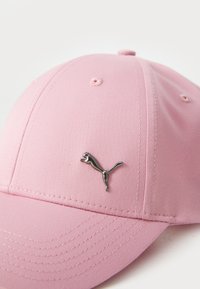 Pink baseball cap with smooth fabric, six ventilation eyelets, and a metallic silver Puma logo on the front. Lightweight and structured shape.