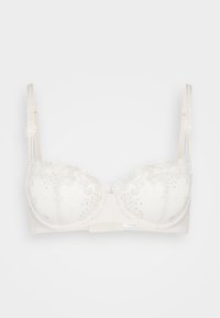 Soutien-gorge sans fil en beige clair avec une bordure en dentelle et des embellissements argentés. Il dispose de bonnets rembourrés, de bretelles réglables et d'une fermeture à crochets au dos.