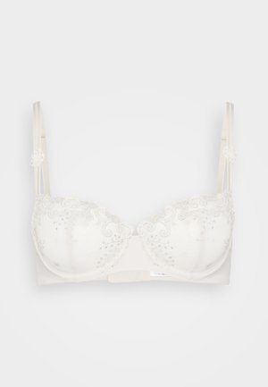 Wireless bra in light beige with lace trim and silver embellishments. Features padded cups, adjustable straps, and a hook back closure.
