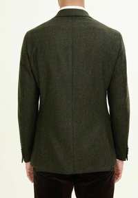 Dunkelgrüner Fischgrät-Blazer mit strukturierten Schultern, Reverskragen und zwei Knöpfen. Der Stoff zeigt eine strukturierte Oberfläche und einen maßgeschneiderten Schnitt.