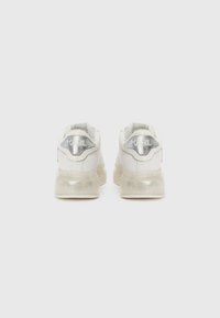 Zapatillas blancas con suela translúcida, que presentan un acento plateado en el talón y la marca "KARL". Parte superior de cuero liso con un diseño elegante.