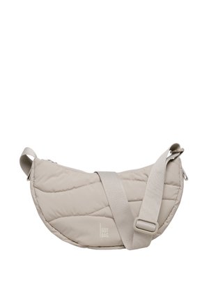 Sac bandoulière beige matelassé avec une large sangle réglable, doté d'une fermeture éclair et d'un logo discret. Surface lisse et texturée.