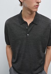 Polo shirt grigio scuro realizzato in tessuto morbido con colletto classico, dotato di tre bottoni e maniche corte, progettato con una vestibilità comoda.