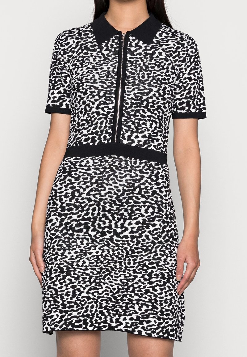 Robe à manches courtes imprimée léopard noir et blanc, avec une fermeture éclair à l'avant et une coupe ajustée, dotée d'une ceinture noire unie.