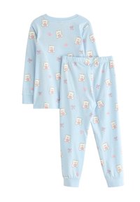 Ljusblå bomullspyjamas med ett upprepat mönster av nallebjörnar med rosa hjärtan och rosetter. Långärmad tröja och byxor med elastiskt midjeband.