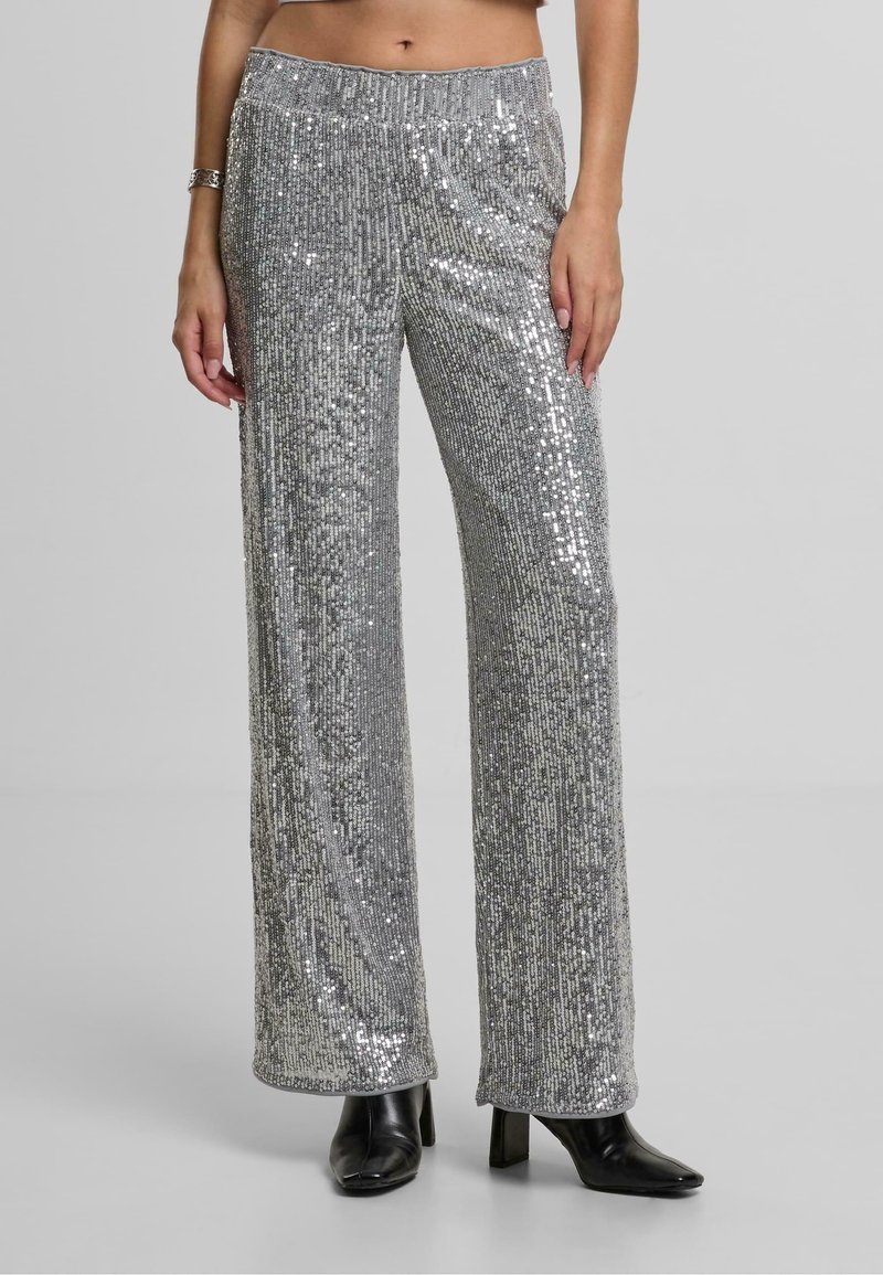 Srebrne široke hlače sa sequins detaljima i elastičnim pojasom, s vertikalnim prugama i glatkom teksturom, uparene s crnim čizmama na visoku petu.