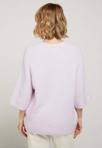Pull oversized lilas avec une texture confortable, manches larges et encolure arrondie, affichant un design simple et épuré.