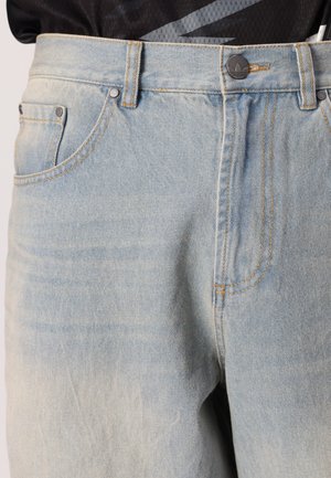 Lichtblauwe spijkerbroek met een hoge taille, vijf zakken en contrasterende oranje stiksels. Voorzien van metalen knopen en een licht vervaagde textuur.