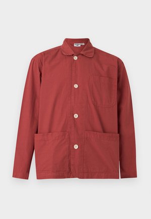 Veste à manches longues couleur rouge rouille avec boutons, col, une poche poitrine et deux poches frontales basses, posée à plat sur fond blanc.