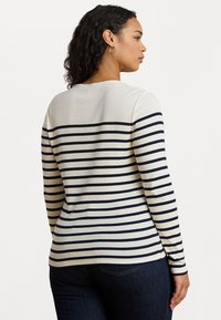 Maglione a maniche lunghe a righe in crema e blu navy, con scollatura rotonda e silhouette aderente caratterizzata da righe orizzontali.