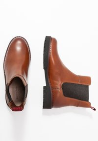 Bottines en cuir marron avec des panneaux latéraux élastiques, semelle en caoutchouc et couture décorative. Dotées d'une languette pour un enfilage facile.