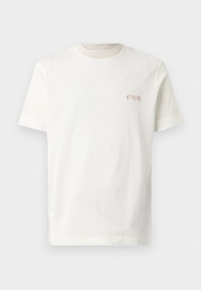 T-shirt de algodão branco com decote redondo. Apresenta um ligeiro canelado à volta do pescoço e um pequeno logotipo bordado no lado esquerdo do peito.